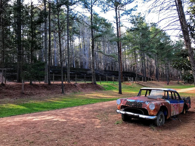 A derelict race car sits below the old stands