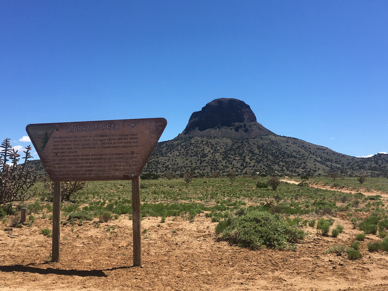 Cabezon Peak looms in the background as the BLM sign in the foreground marks the turnoff to the unpaved road leading to the parking area at the trailhead.