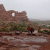 Two hikers approach the North Window Arch.