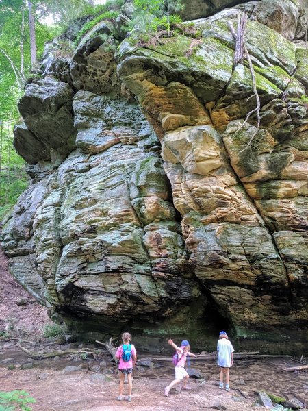 Girl's exploring  stream under large rock formation.