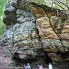 Girl's exploring  stream under large rock formation.