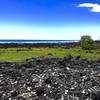 The trail winds along the coast. Intermixed with the black igneous rocks are bleached coral skeletons.