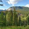 Mountains come into view along the forested North Boundary Trail, as the trail climbs.