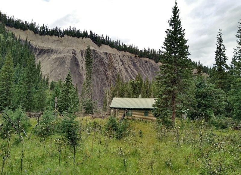 The Shalebanks Warden Cabin comes into view in a clearing in the fir forest, deep in the Jasper National Park backcountry.