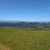 The blue Santa Cruz Mountains are in the distance with Loma Prieta, 3,790 ft., the highest, on the left. Nearer, are the spring green hills of Joseph D. Grant County Park.  Seen looking southwest from high on Los Huecos Trail.