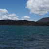 Cinder Cone rises in the distance as the Fantastic Lava Beds come right up to the water.  Kayakers, paddleboarders, and fishermen can be seen on the lake.