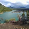 Rising above Butte Lake (left to right) are Sunrise Peak, Ash Butte, and Mt. Hoffman. The islands and boulders on the right shore are fantastic lava beds from slow cooling lava of cinder cone eruptions. Looking south from the north end of Butte Lake.