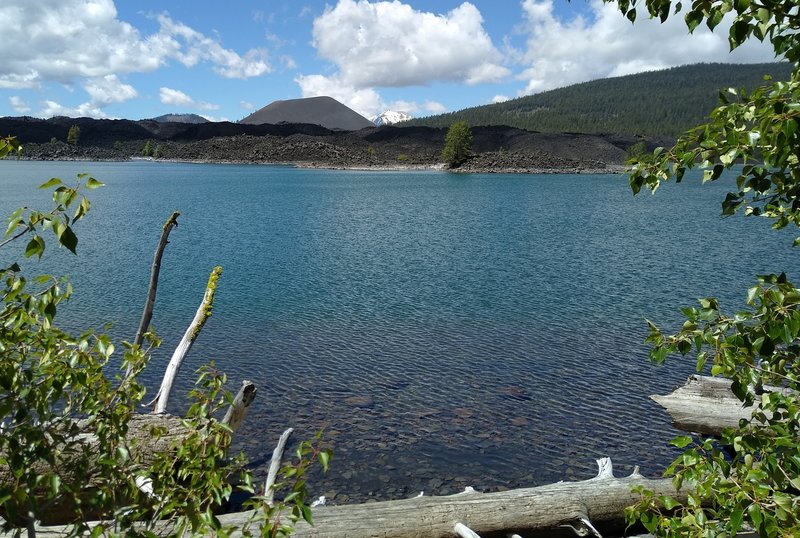 Left to right in the distance across Butte Lake are Fairfield Peak (7,272 ft.), Cinder Cone (6,907 ft.), snowy Lassen Peak (10,457 ft.), and part of Prospect Peak (8,338 ft.). The black boulders forming the far shoreline are Fantastic Lava Beds.