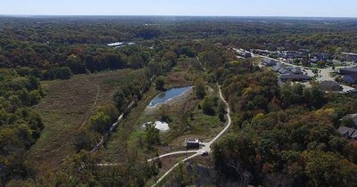 Drone footage, looking due west.  M-K-T trail to the left of photo, loop trail and Forum Connector to the center right.