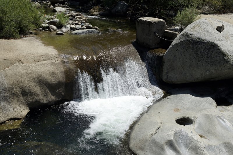 A small waterfall above the swinging bridge flows fast even in the summer.