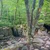 The Shades of Death trail descends through a narrow rocky slot to continue following the stream.