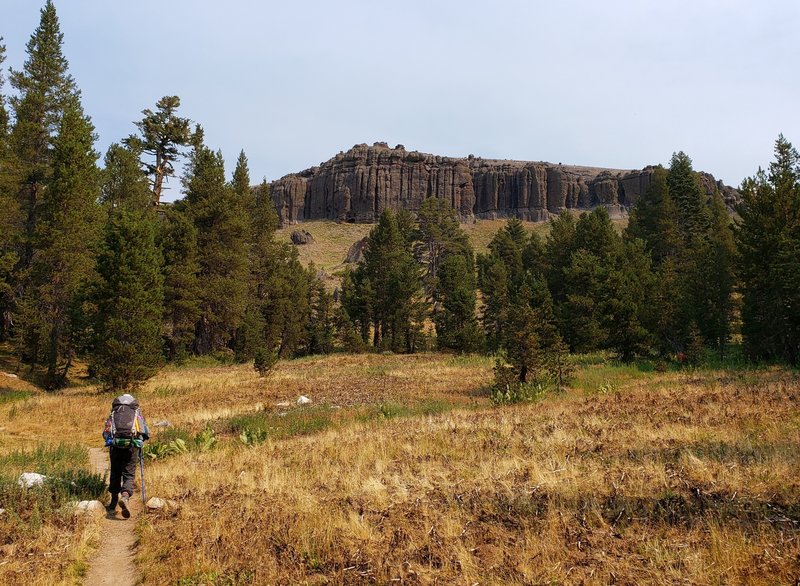 Wooded area opens up revealing dramatic cliffs.