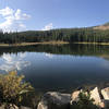 Clouds reflect on a perfectly still inky lake.