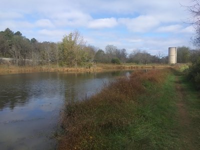 Fall view of pond with train tracks and silo in background.