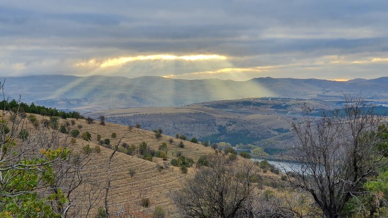 Sun shining down through an aperture among dense clouds during autumn.