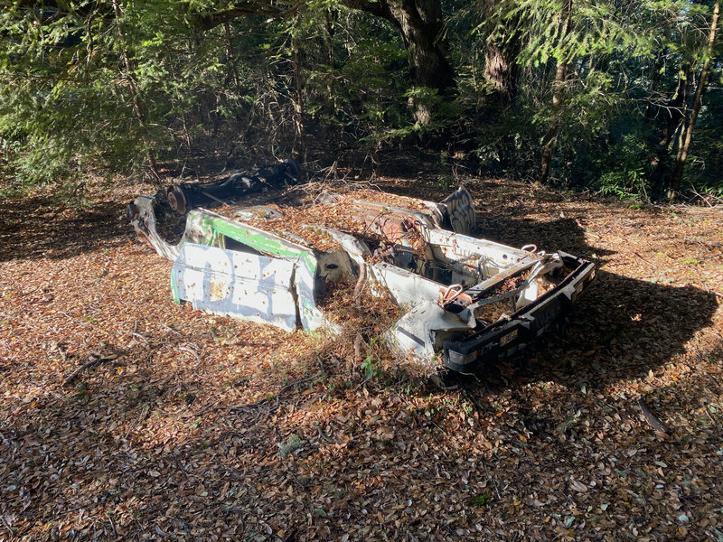 An old car sits along the side of the trail, flipped over and spray painted.