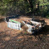 An old car sits along the side of the trail, flipped over and spray painted.