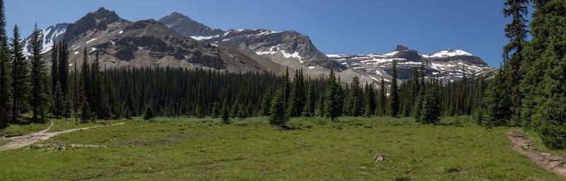 The meadow backed by rocky peaks taken from the picnic tables in front of the Stanley Mitchel Hut.