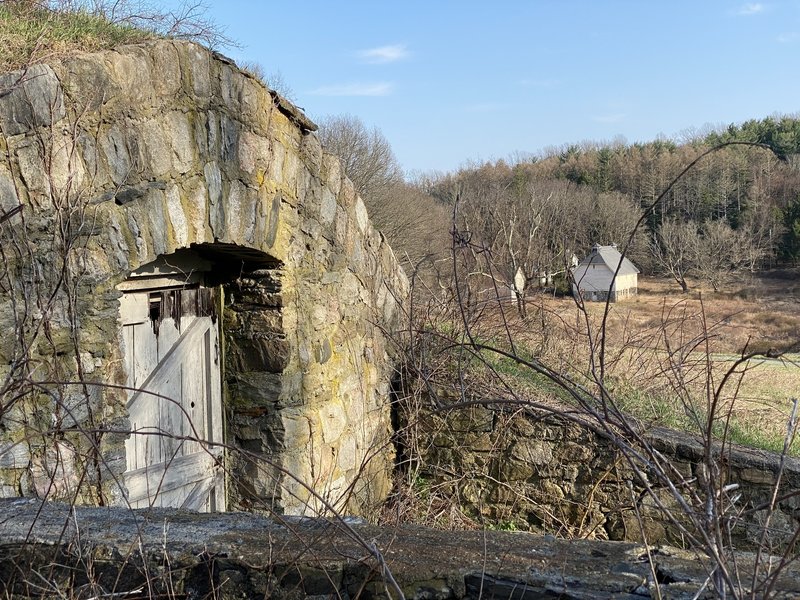 Root cellar with farm buildings in distance.