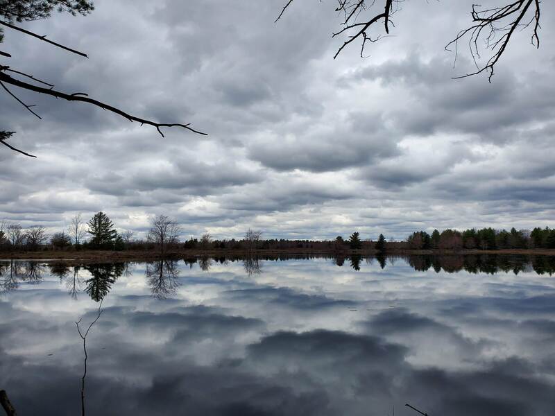 Cloudy skies reflected on a still lake.