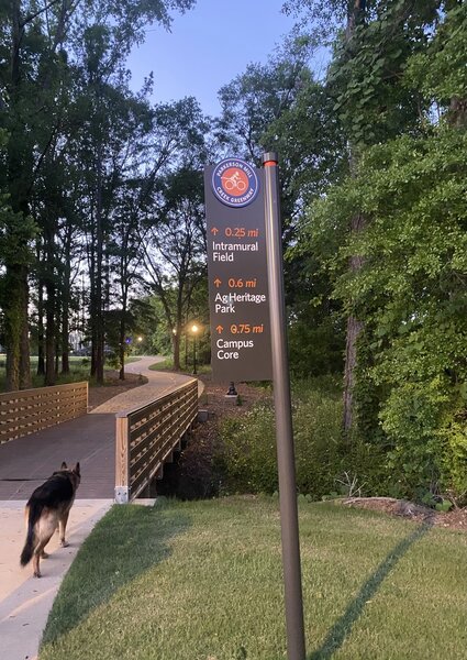 Directional sign for the Parkerson Mill Creek Greenway right before a small foot bridge.