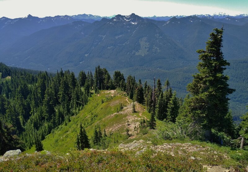 A bird's eye view of Wenatchee Ridge Trail below from a lookout up higher along the trail.  Rugged mountains stretch into the far distance in all directions.