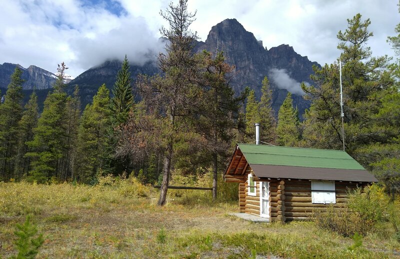 The Chaba Warden Shelter with Dragon Peak jutting up behind it from the other side of the Athabasca River.