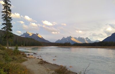 The Chaba River (right far valley) empties into the Athabasca River (center far valley) in front of unnamed center peak with snow capped Mount Quincy behind it on right. Seen looking south/upstream on the banks of the Athabasca at Big Bend trail camp.