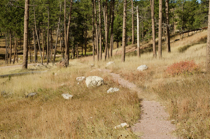 The trail descends along a gravel trail toward the historic area of the park.