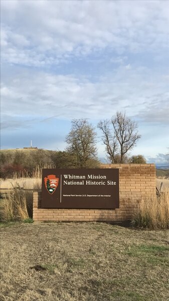 The park sign with the monument in the background.