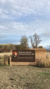 The park sign with the monument in the background.