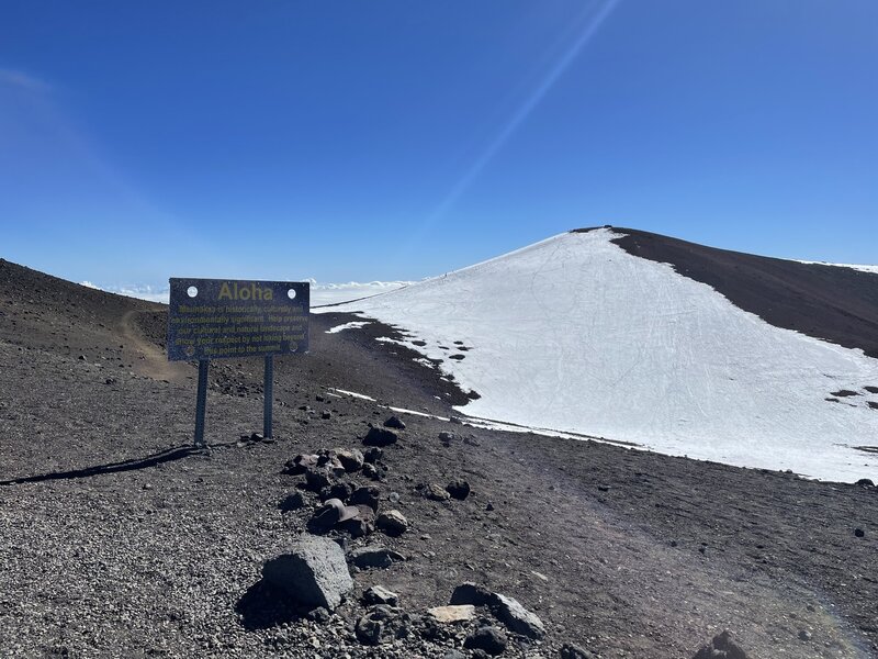 Maunakea summit with sign. It is not recommended to go to the actual summit for safety and cultural reasons. Winter ice and a sacred Hawaiian site are great reasons to view from afar.