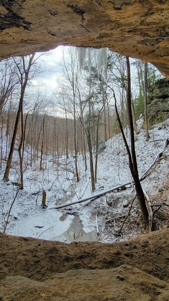 Snow covered valley from under rock shelf.