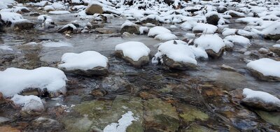 Snow covered rocks in icy creek.