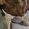 A large boulder suspended over the trail and supported by smaller rock.