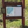 Whitney lake trailhead sign, it's partially obscured by trees from the road.