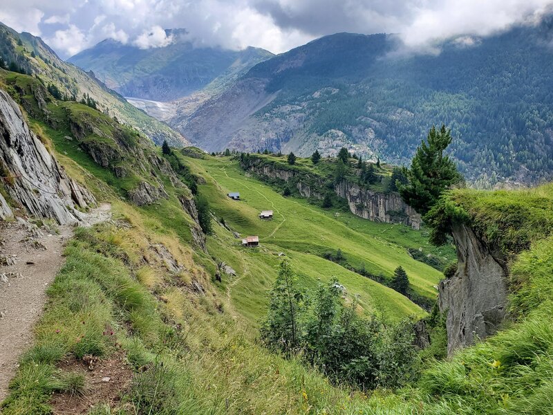 Green pastures and scattered huts high on the hillside.