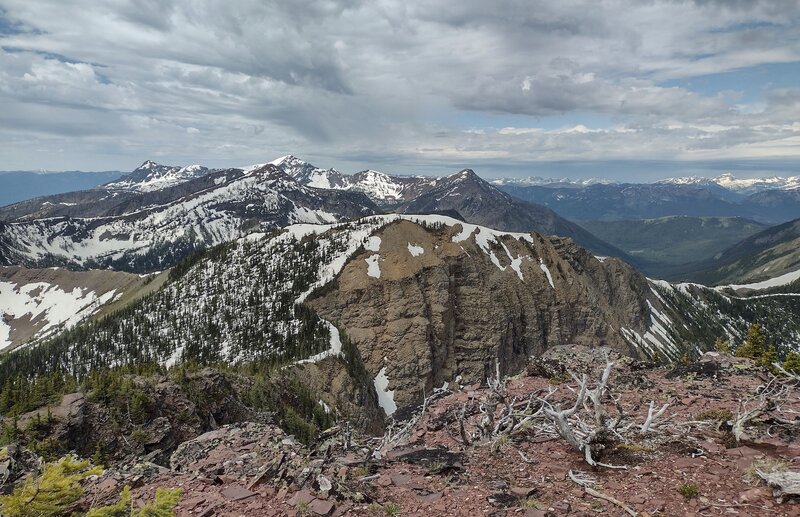 On Peak #4 summit looking southwest: Peak #5 is the nearby brown faced peak behind red summit of Peak #4 with ridge connecting the two peaks winding to lower left. The saddle at far right is where the trail attains the ridge and follows it to Peak #5.