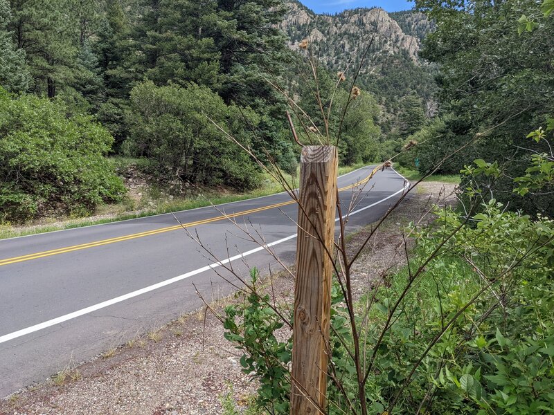 Trailhead to left.  Post where trailhead sign used to be. Mile marker 293 in background to right of post.