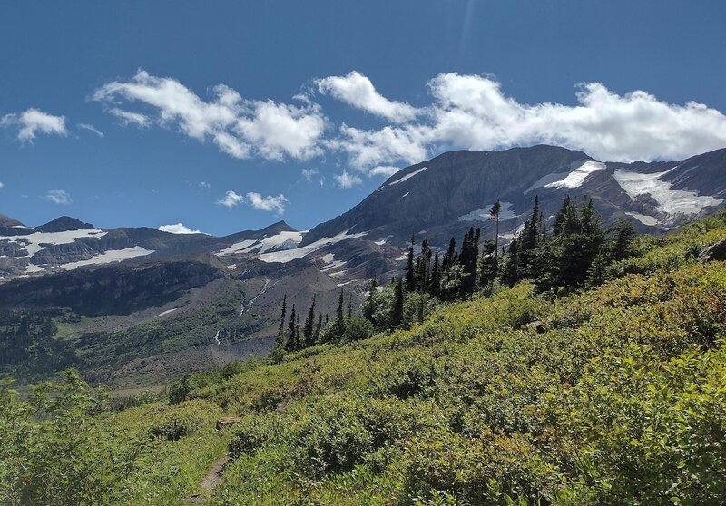 An arm of Jackson Glacier is seen at the far right, with the rest of the glacier not visible from this angle. Blackfoot Glacier and its runoff are center-left, also with much of it not visible from here at the end of Jackson Glacier Trail.