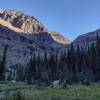 Headwaters of Sprague Creek are seen cascading down from Sperry Glacier - center right, and running through this meadow, lower left.  Sunlit Edward Mountain (left) and Lincoln Peak ridges (right) are walls of the gap that the creek cascades down from.