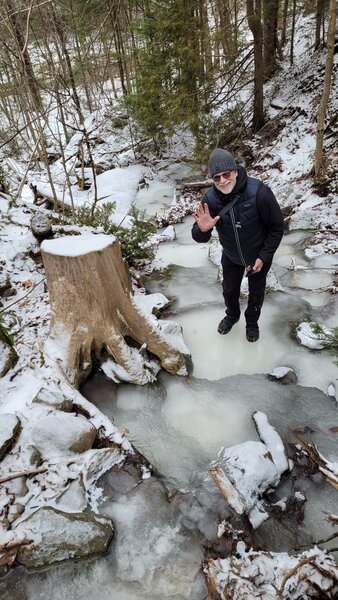 My friend Marc who is in a frozen stream with crampons on his foot.