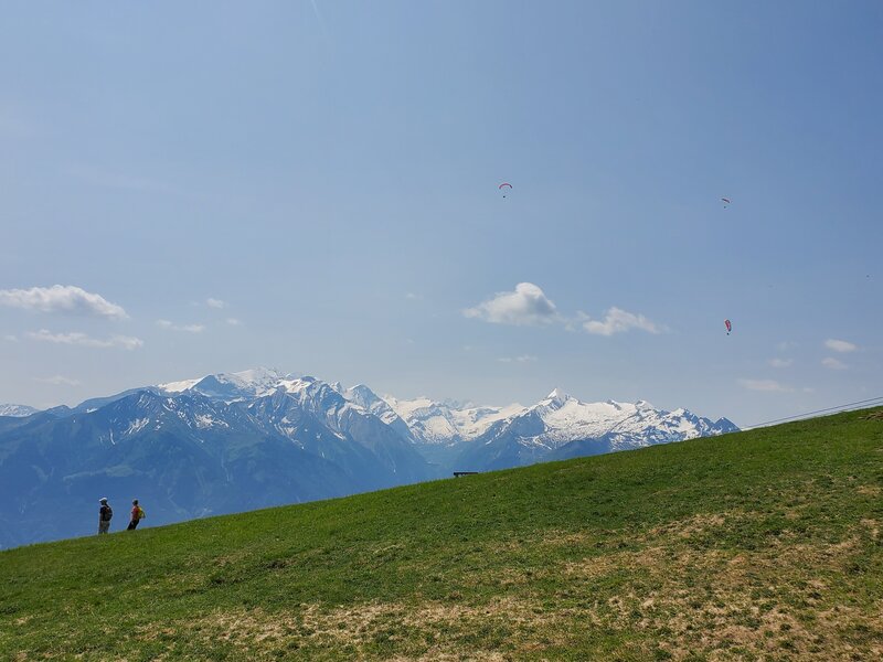 Paragliders in the sky, hikers on the ridge.