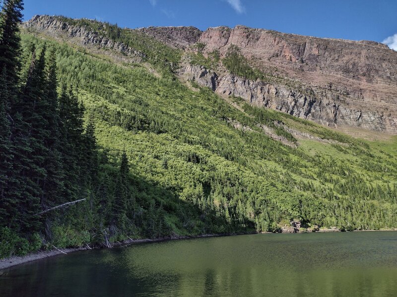 The steep, forested shoreline of Lost Lake, rises to rock walls capped by the Great Divide.