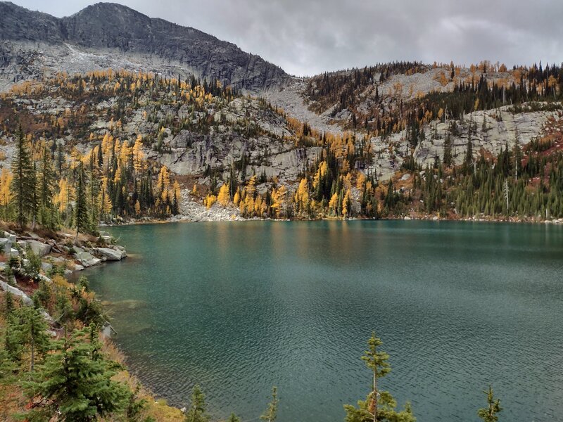 The gorgeous aquamarine color of the upper/third Roman Nose Lake, as sunlight strikes it. Also lighting up the golden larches on cliffs above the lake, As Roman Nose Peak, 7,260 ft., presides over all this beauty.