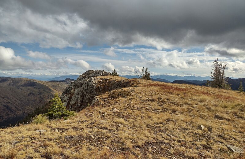 Mount Pend Oreille summit block with scary cliffs on its north side. More of the Cabinet Mountains can be seen in the distance to the east.