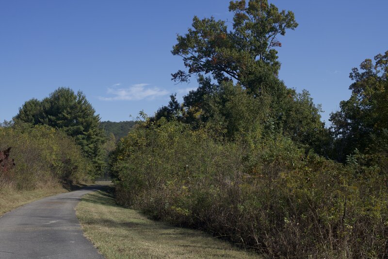 The paved trail descends gently toward the blockhouse.