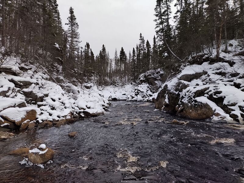 Rivière des Rapides encaisser entre deux massifs rocheux enneigés. River of rapids encased between two snowy rocky massifs.