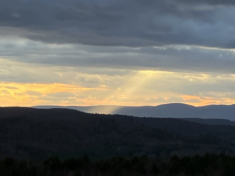 The last rays of sunlight, shining on a distant hill.