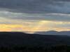 The last rays of sunlight, shining on a distant hill.